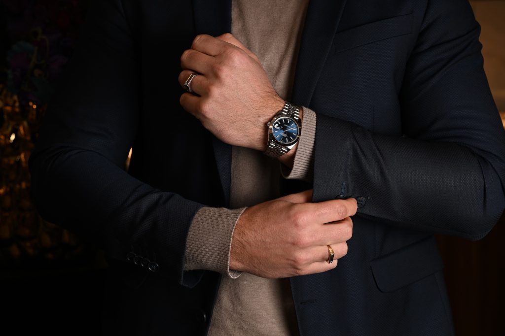 Man in pak draagt een Rolex Datejust, close-up van pols en horloge